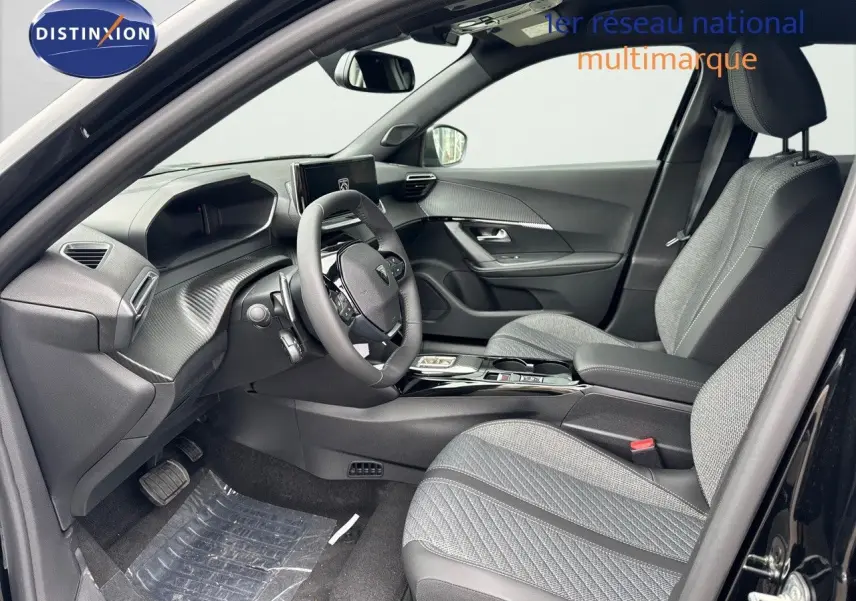Intérieur avant du Peugeot 2008 noir métal 2025, sièges tissu gris, tableau de bord moderne et volant compact.