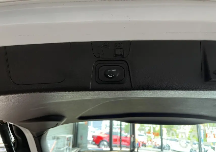 Gros plan sur la commande d'ouverture du hayon intérieur d'une Ford C-MAX blanche, vue depuis le coffre.