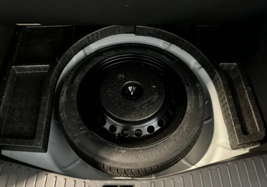 Gros plan sur la roue de secours galette noire dans le coffre blanc d'une Ford C-MAX Titanium 2018.