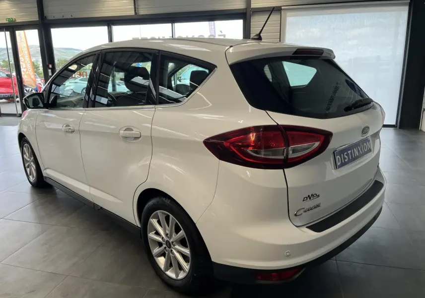 Vue 3/4 arrière droit d'un Ford C-MAX blanc avec jantes alliage et toit panoramique en showroom.
