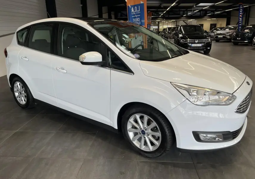 Vue 3/4 avant droit d'une Ford C-MAX blanche avec jantes alliage et toit panoramique en showroom.