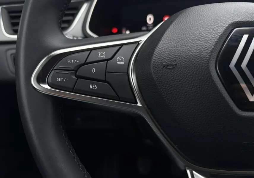 Gros plan sur le volant noir du Renault Captur 2025, mettant en valeur les commandes de régulateur de vitesse côté gauche.