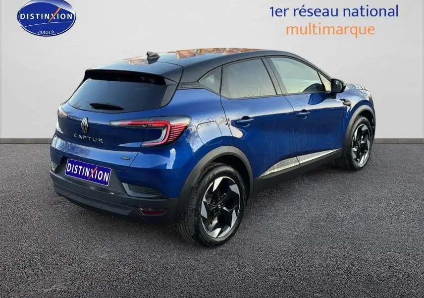 Renault Captur 2026 bleu iron et noir, vue 3/4 arrière droit, jantes alu noires et toit noir contrasté.