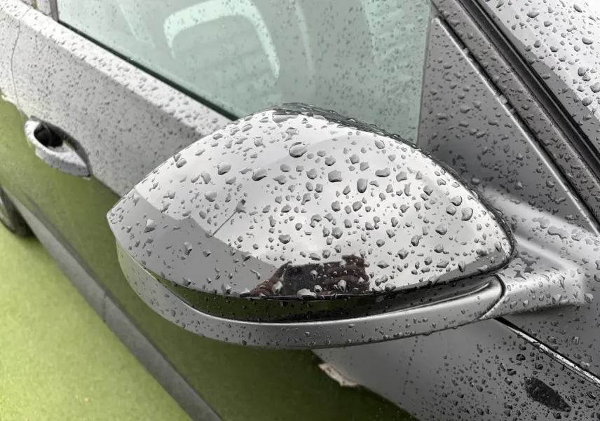 Rétroviseur droit noir métallisé de Citroën C5 Aircross 2026 avec gouttes de pluie sur la carrosserie noire.