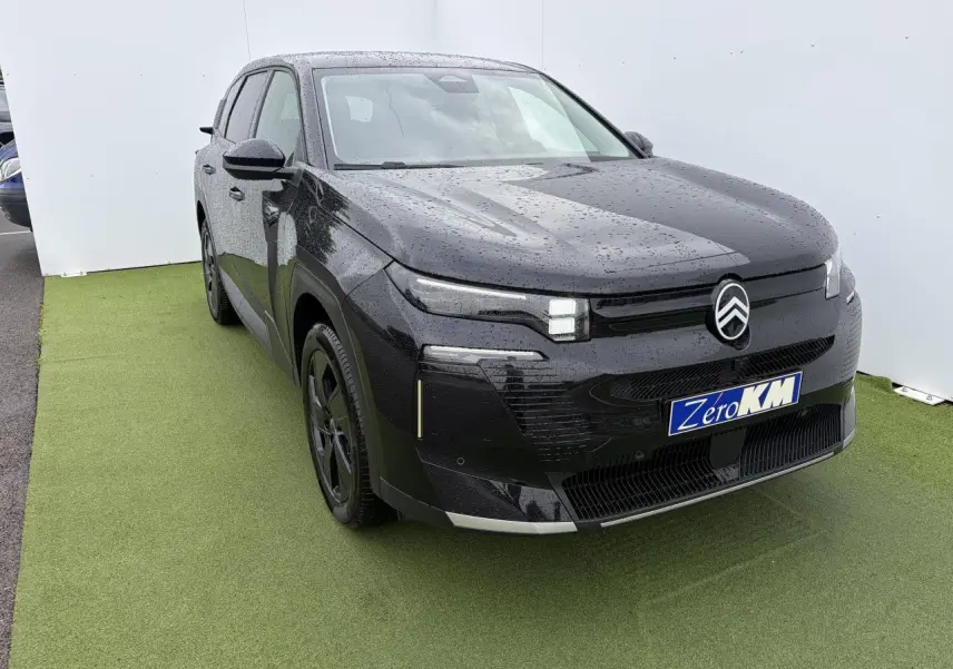 Citroën C5 Aircross noir métal en 3/4 avant droit, avec pluie visible sur la carrosserie et jantes noires.