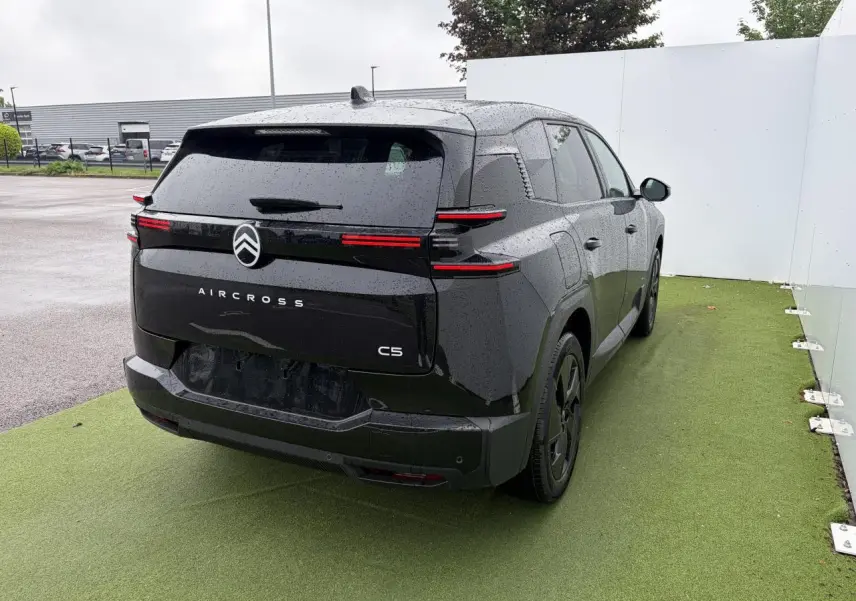 Vue 3/4 arrière droite d'un Citroën C5 Aircross noir métal avec feux arrière LED fins et toit panoramique visible.