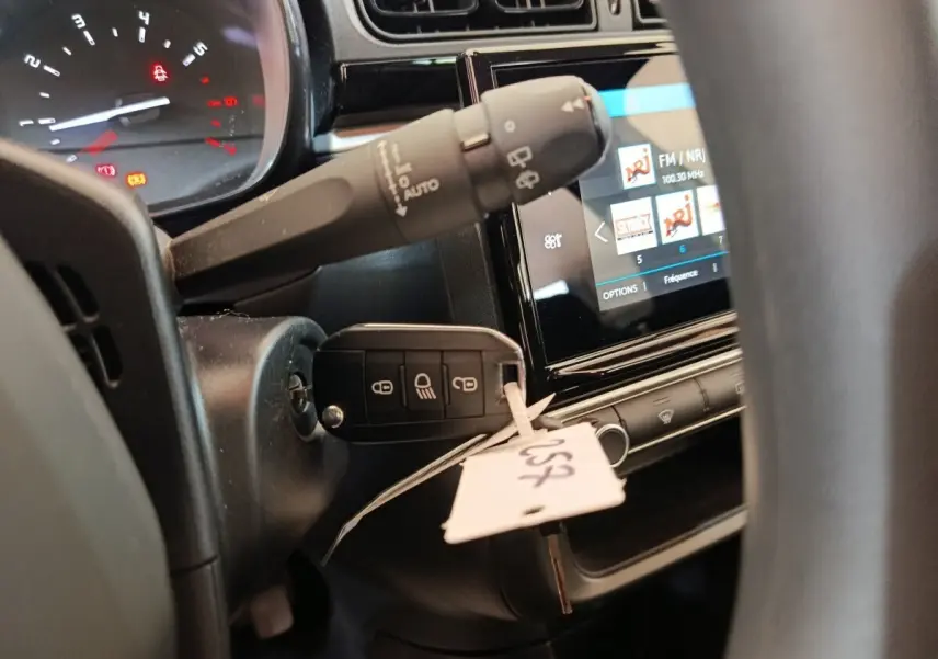 Gros plan intérieur côté conducteur sur le tableau de bord et la clé insérée d'une Citroën C3 blanche, écran tactile visible.