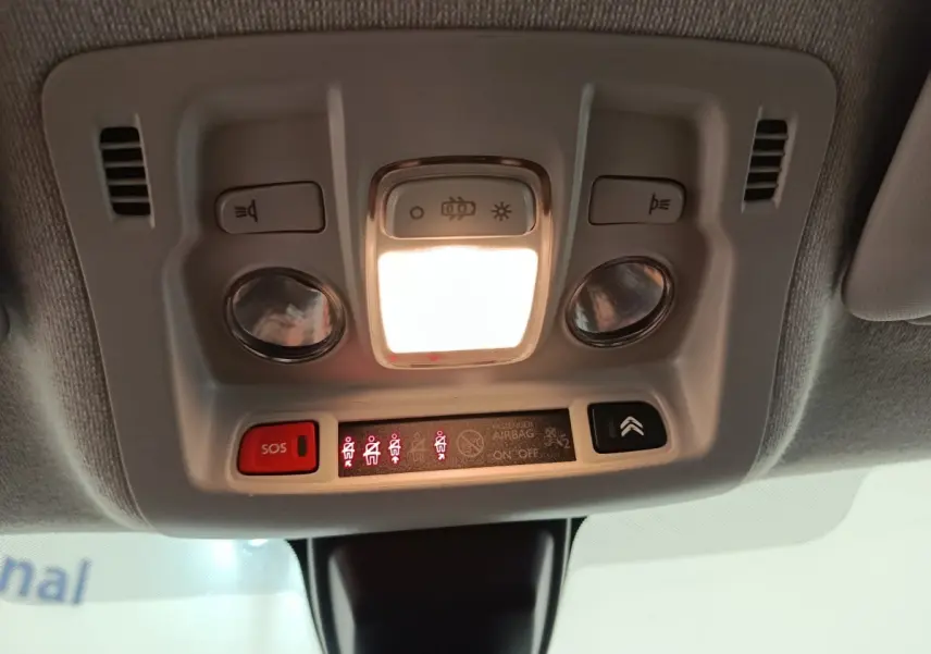 Vue en contre-plongée du plafonnier blanc de la Citroën C3 2020 avec éclairage et boutons SOS et airbag.