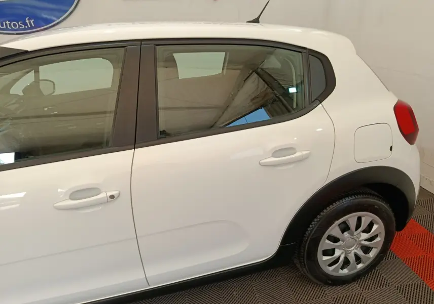 Vue latérale côté droit d'une Citroën C3 blanche de 2020, avec poignées de porte et jante acier visible.