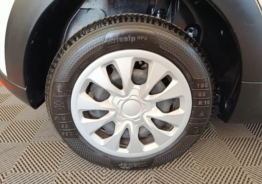 Gros plan sur la roue avant droite d'une Citroën C3 blanche, mettant en valeur la jante avec enjoliveur gris.