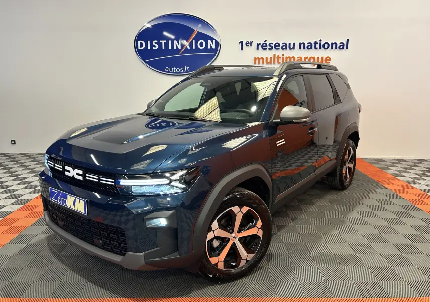 Vue 3/4 avant du Dacia Bigster bleu indigo avec jantes bi-ton et toit ouvrant en showroom.
