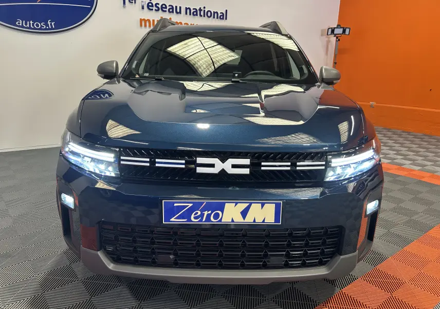 Vue frontale du Dacia Bigster bleu indigo avec phares LED allumés et calandre noire distinctive.