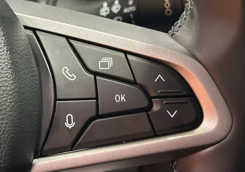 Gros plan sur les commandes multifonctions noires du volant du Dacia Bigster, entourées d’un cadre gris argenté.
