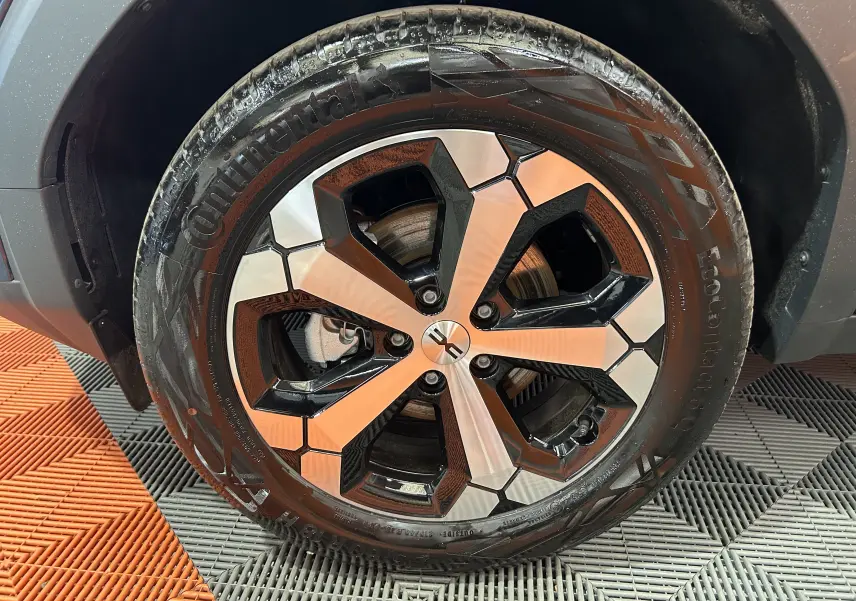 Gros plan sur la roue avant droite de la Dacia Bigster bleu indigo, avec jante alliage bicolore et pneu Continental.