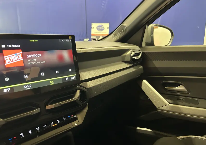 Intérieur du Dacia Bigster 2026 côté passager, avec tableau de bord moderne et écran tactile affichant la radio Skyrock.