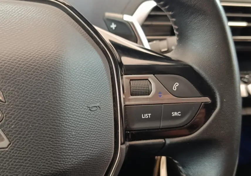 Gros plan sur le volant cuir noir de la Peugeot 5008 2020, avec commandes multifonctions et molette tactile à droite.