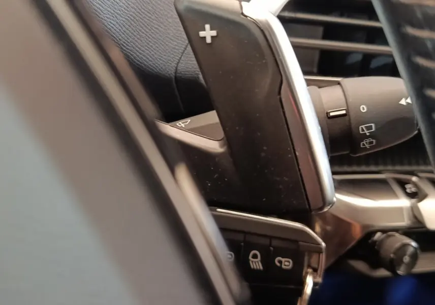 Gros plan sur la commande de palette de changement de vitesse au volant du Peugeot 5008 noir, intérieur cuir noir.