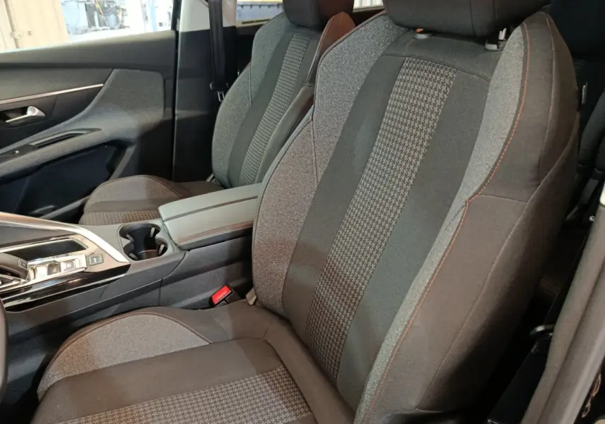 Vue intérieure rapprochée des sièges avant gris avec surpiqûres orange du Peugeot 5008 noir, version Active Business.