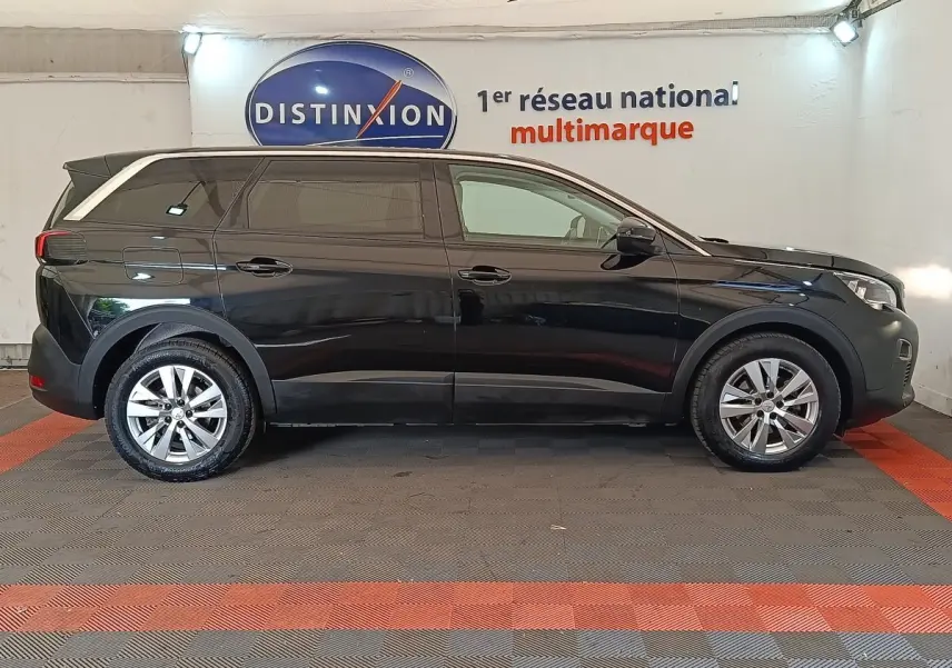 Profil côté gauche d'un Peugeot 5008 noir 2020, SUV avec vitres teintées et jantes alliage en intérieur showroom.