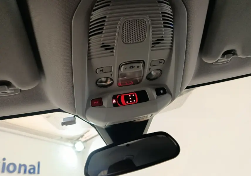 Vue intérieure en plongée du plafonnier et du rétroviseur central du Peugeot 5008 noir, avec commandes lumineuses activées.