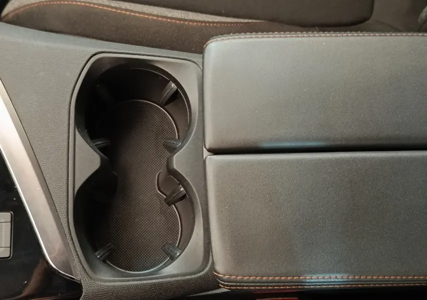 Gros plan sur la console centrale noire du Peugeot 5008 2020, avec porte-gobelets et accoudoir en cuir noir à surpiqûres marron.