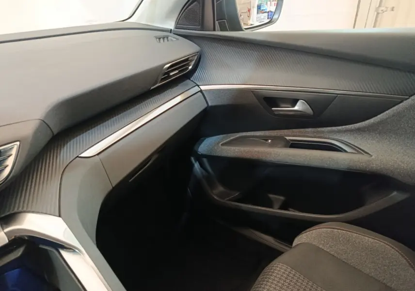 Vue intérieure côté passager du Peugeot 5008 2020 noir, avec tableau de bord et garnitures en finition carbone.