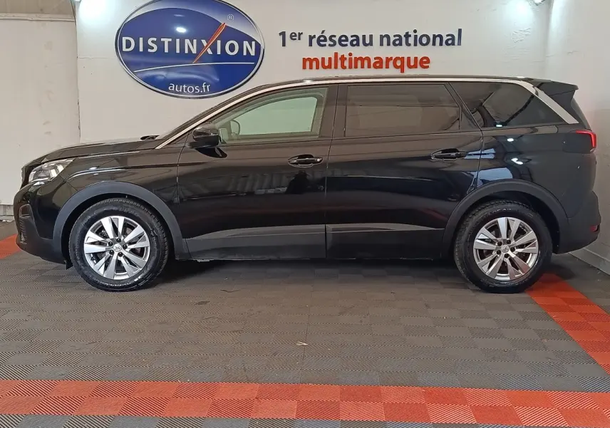 Vue de profil côté gauche d'un Peugeot 5008 noir 2020 garé en intérieur avec jantes alliage et vitres teintées.