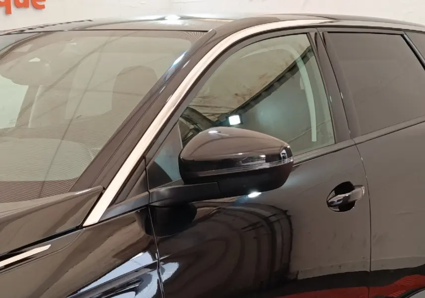 Vue rapprochée du côté gauche avant du Peugeot 5008 noir, mettant en valeur le rétroviseur et la portière.