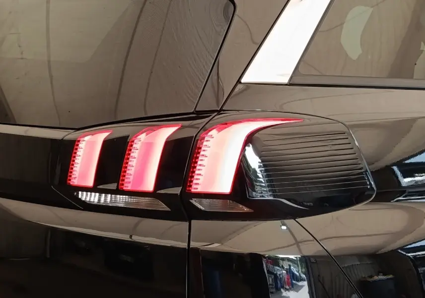 Gros plan sur les feux arrière droits allumés d’un Peugeot 5008 noir, soulignant les lignes modernes du véhicule.
