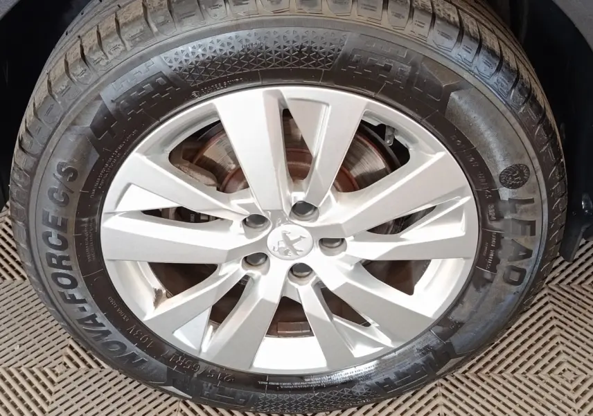 Gros plan sur la roue avant droite du Peugeot 5008 noir, mettant en valeur la jante alliage argentée et le pneu.