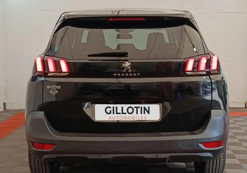 Vue arrière d'un Peugeot 5008 noir de 2020 avec feux LED allumés et logo Peugeot visible.