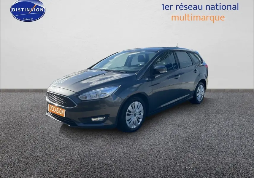 Ford Focus SW gris magnetic metal vue 3/4 avant droit sur sol bitumé avec plaque occasion orange visible