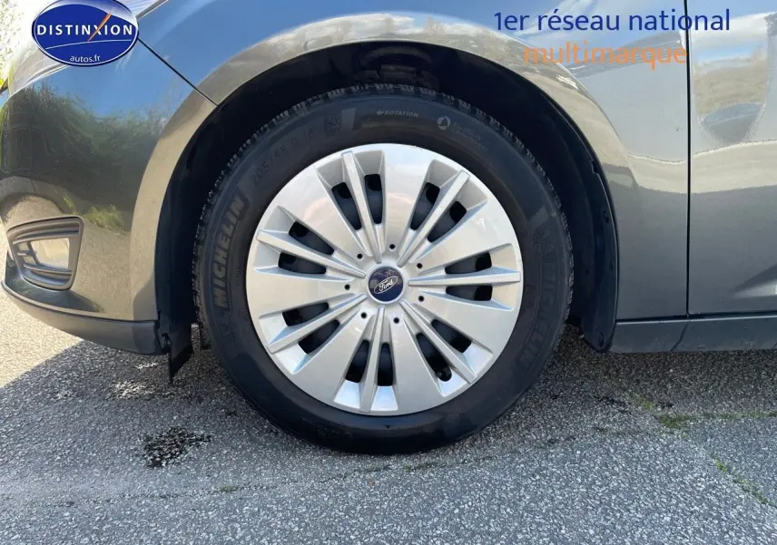 Gros plan sur la roue avant gauche d'une Ford Focus SW gris magnetic metal, mettant en valeur la jante et le logo Ford.