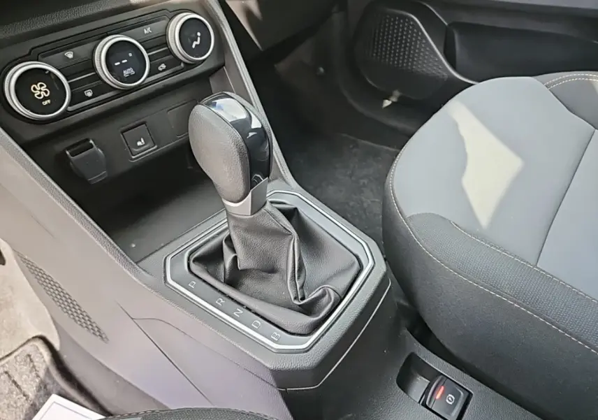 Le levier de boîte automatique noir du Dacia Jogger Extreme Hybrid vu de dessus, avec console et sièges gris.