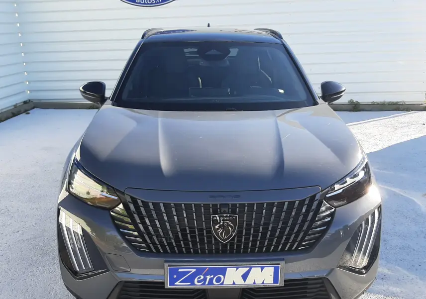 Vue frontale d'un Peugeot 2008 gris selenium avec calandre noire et feux LED verticaux allumés.