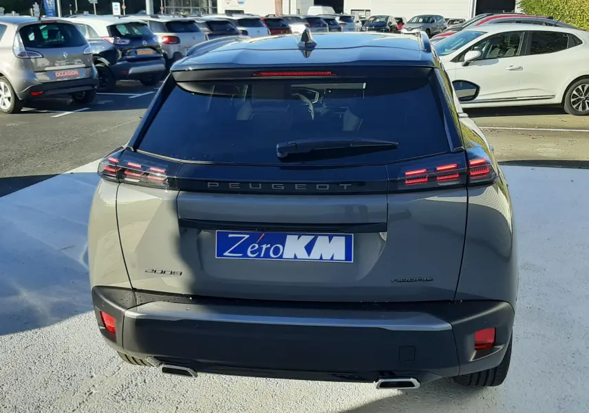 Vue arrière d'un Peugeot 2008 gris selenium hybride avec feux LED et double sortie d'échappement sur parking.