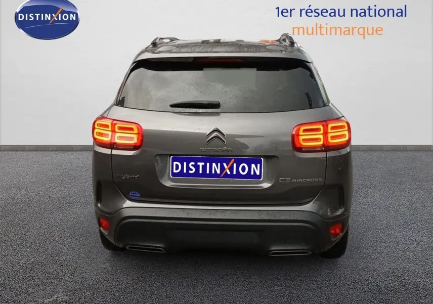 Vue arrière d'un Citroën C5 Aircross hybride rechargeable gris platinium avec feux allumés, en stationnement.