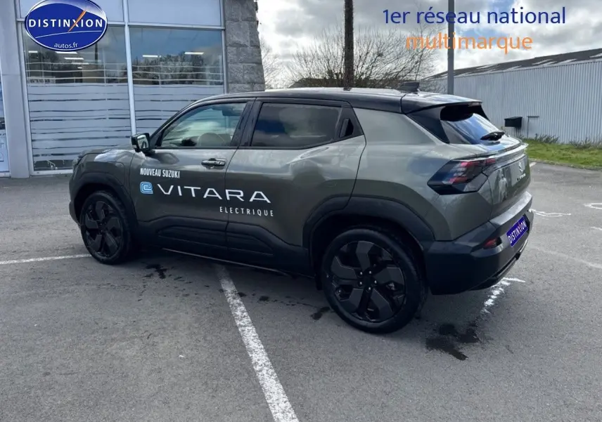 Suzuki Vitara électrique 2026 vert Land Breeze avec toit noir, vue 3/4 arrière côté gauche, jantes noires distinctives.