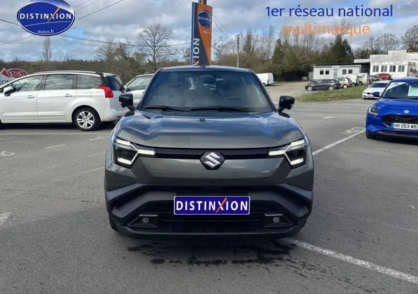 Vue avant d'un Suzuki Vitara 2026 vert foncé avec toit noir, éclairage LED et calandre épurée sur parking.