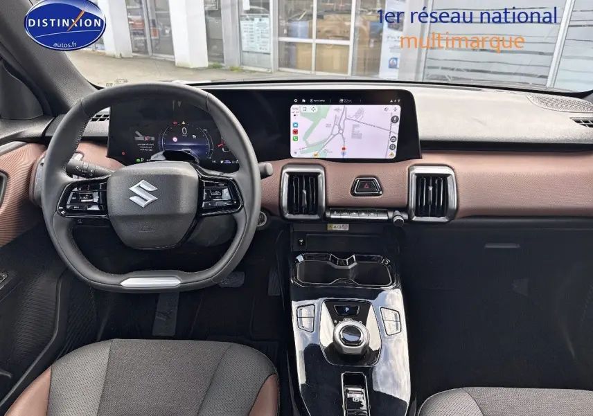Vue intérieure avant du Suzuki Vitara 2026 avec tableau de bord marron et noir, écran tactile GPS et volant multifonction.