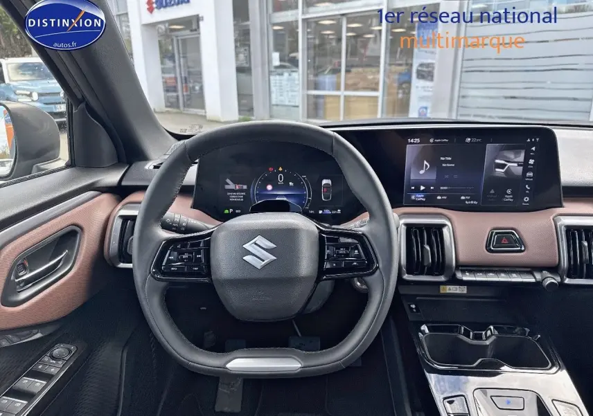 Vue intérieure centrée sur le volant et le tableau de bord du Suzuki Vitara 2026 avec écran tactile et garniture marron.