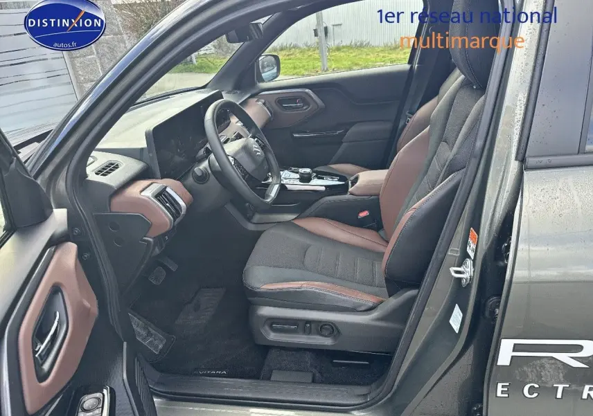 Vue côté conducteur intérieur du Suzuki Vitara 2026 vert Land Breeze avec sellerie tissu/cuir marron et noir.