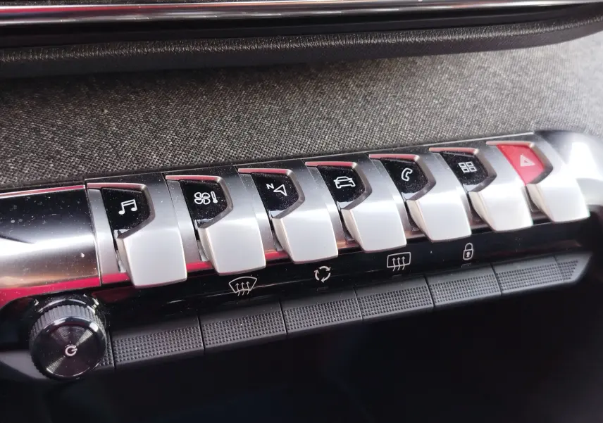 Gros plan sur les boutons de commande argentés et noirs du tableau de bord intérieur du Peugeot 3008 gris Platinium 2023.