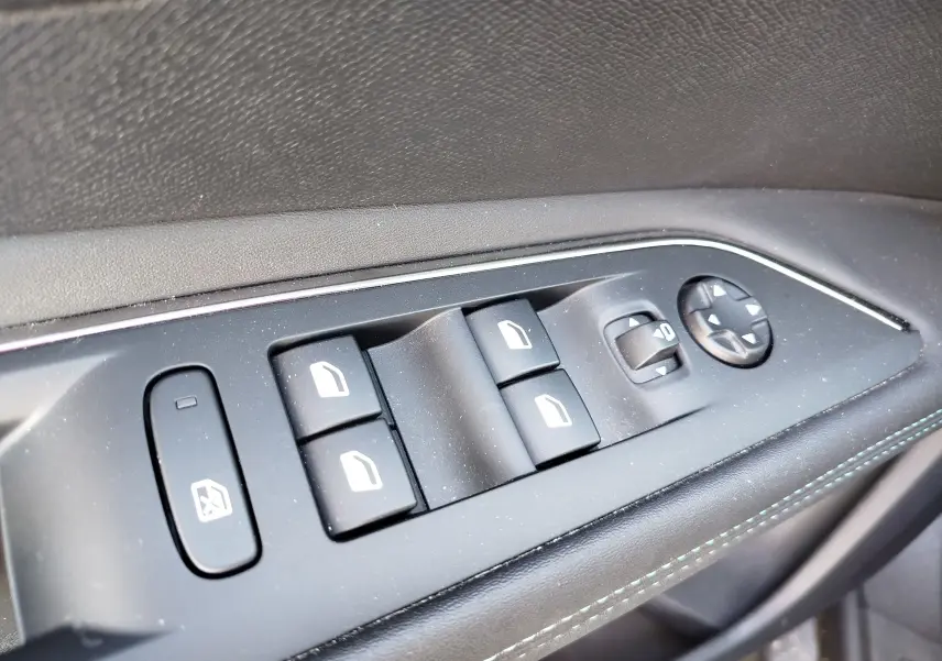 Gros plan sur les commandes des vitres et des rétroviseurs électriques côté gauche intérieur d’un Peugeot 3008 gris Platinium.