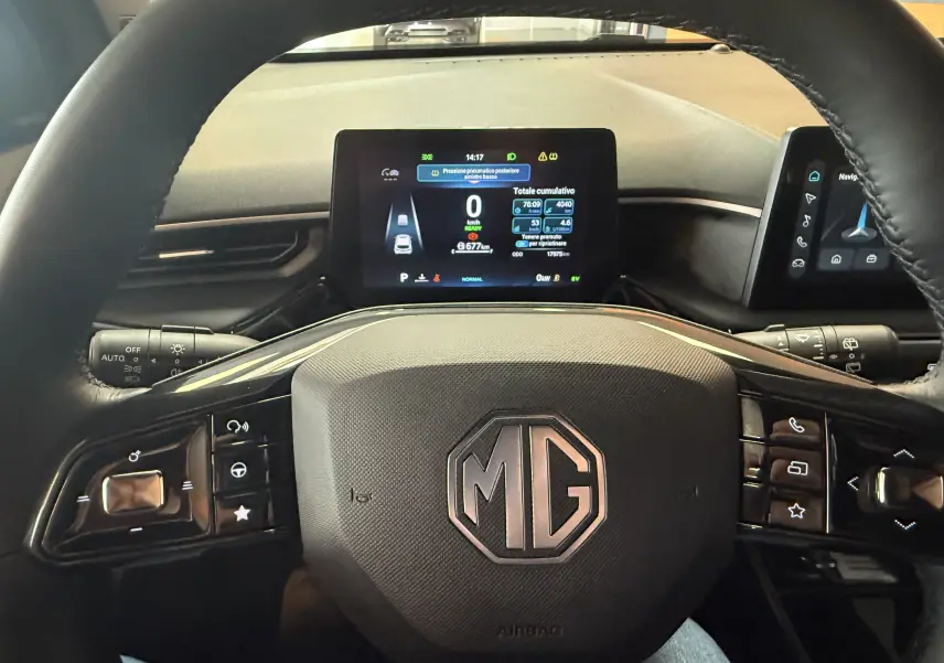 Vue rapprochée du volant en cuir microfibre noir avec logo MG au centre et tableau de bord numérique allumé.