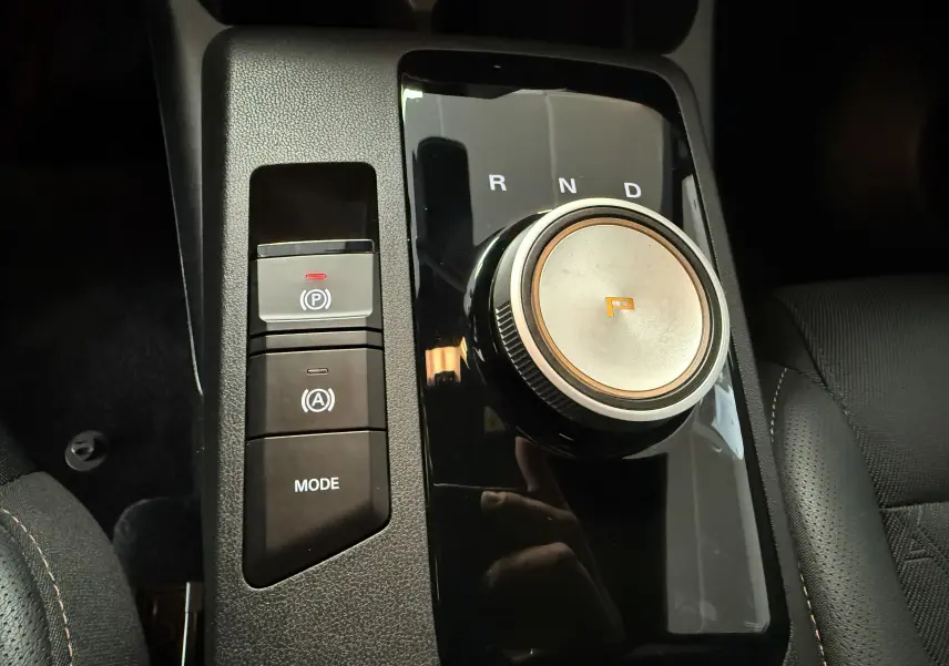 Gros plan sur la molette de boîte automatique et les boutons de contrôle du MG3 Luxury en intérieur noir.