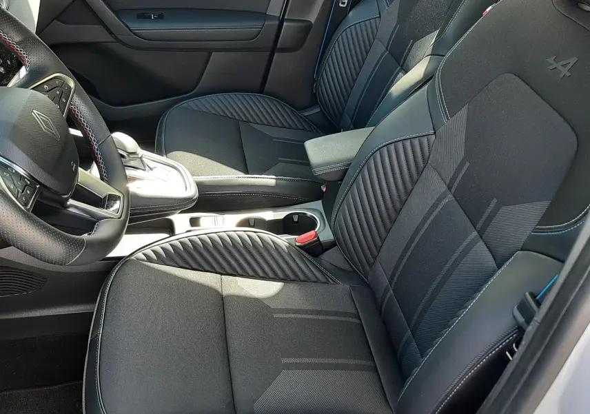 Vue intérieure côté conducteur de la Renault Symbioz E-Tech Full Hybrid 145 Esprit Alpine, sièges noirs avec surpiqûres bleues et logo Alpine brodé.