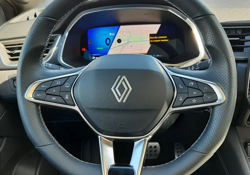 Vue frontale du volant noir perforé du Renault Symbioz E-Tech Full Hybrid 145 Esprit Alpine avec tableau de bord numérique affichant la carte.