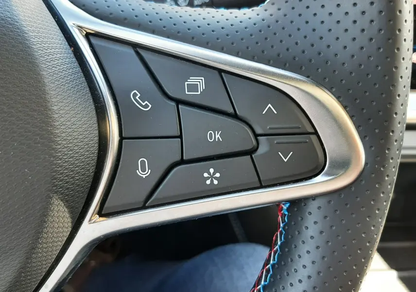 Gros plan sur les commandes gauche du volant perforé noir avec surpiqûres tricolores du Renault Symbioz gris Rafale 2025.