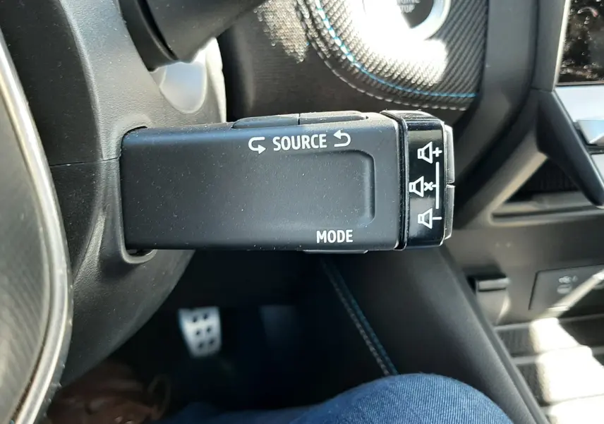 Gros plan sur la commande au volant du Renault Symbioz gris Rafale, mettant en valeur les boutons Source et Mode.